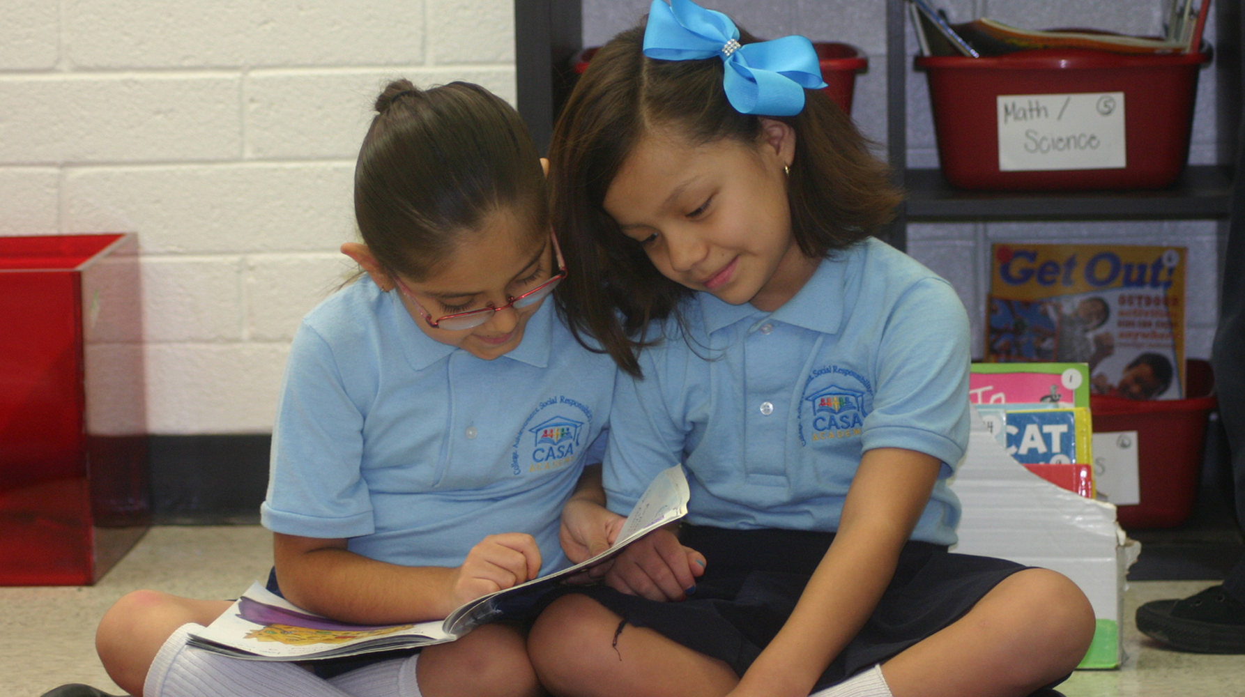 Two young scholars at CASA Academy charter school read together on the carpet