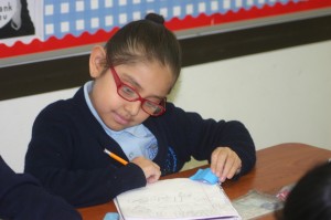 A scholar at CASA academy works hard at her desk