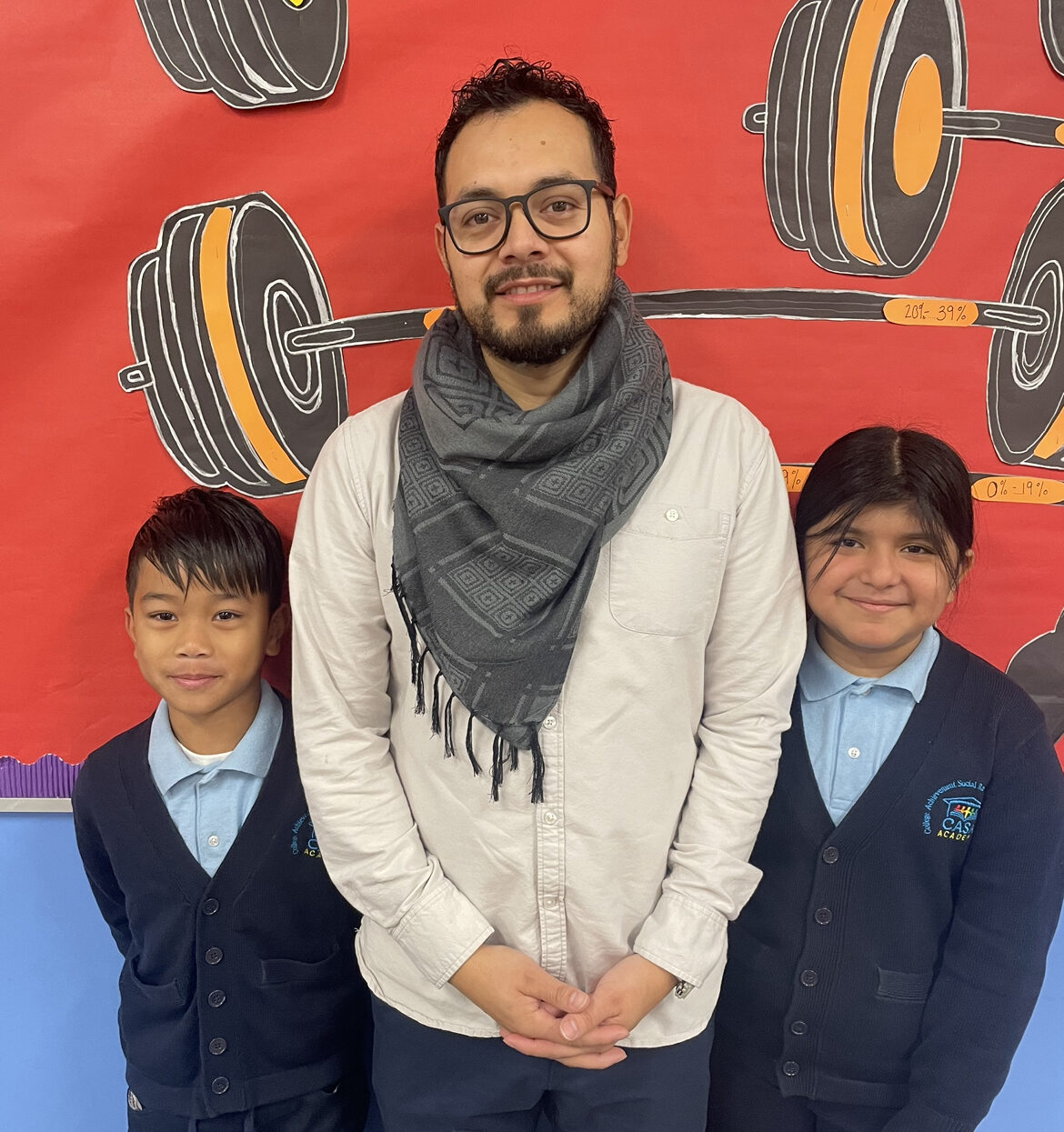 Jonathan Reynoso, a CASA Academy teacher, smiles with 2 students. 